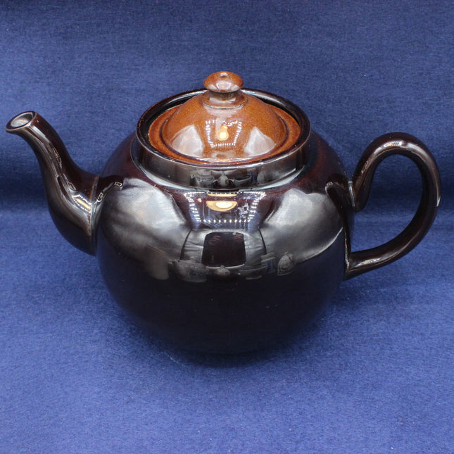 Ceramic teapot with a brown lid on a blue background