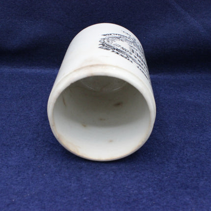 White ceramic cup with black text on a blue fabric background