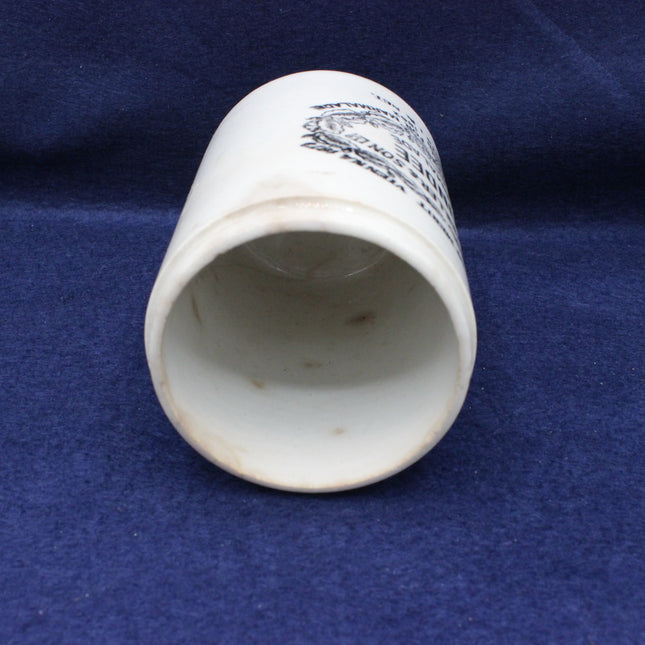 White ceramic cup with black text on a blue fabric background
