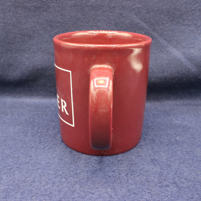 Red mug with a logo on a blue fabric background