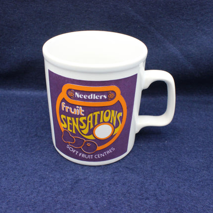 White mug with 'Needler's Fruit Sensations' design on a blue background