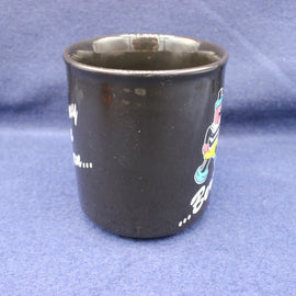Black mug with colorful designs on a blue background