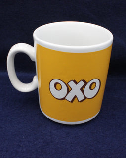 White mug with yellow side featuring 'OXO' logo on a dark blue background