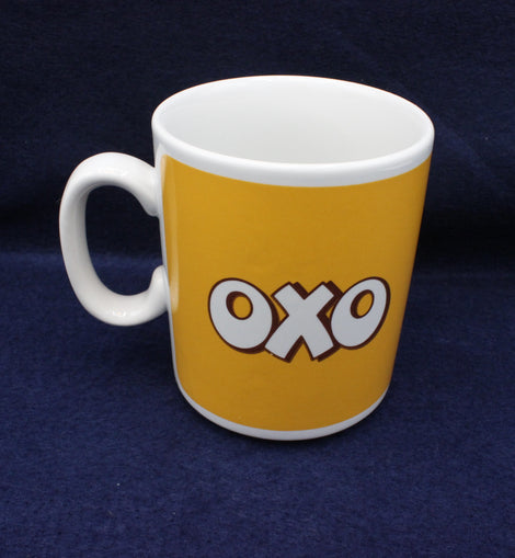 White mug with yellow side featuring 'OXO' logo on a dark blue background