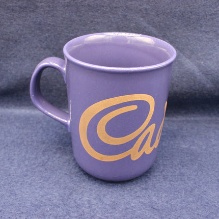 Purple mug with a yellow Cadbury's  logo on a gray background