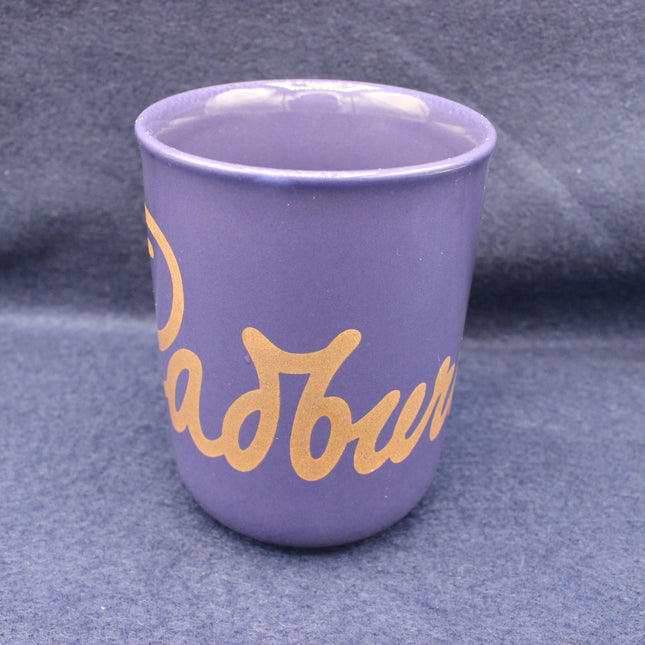 Purple mug with gold text on a grey background