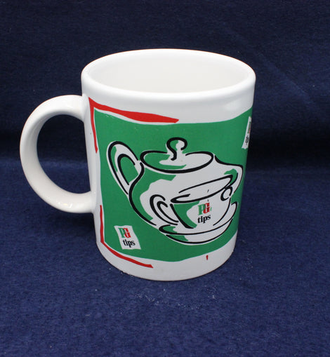 White mug with green and red design featuring a teapot on a blue background