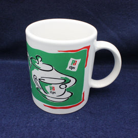 White mug with green and red design on a blue background