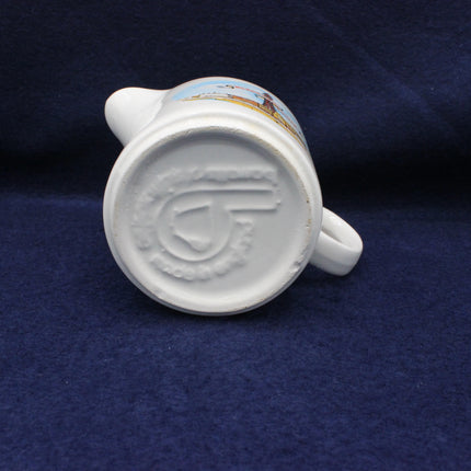 White ceramic mug with a logo on a blue fabric background