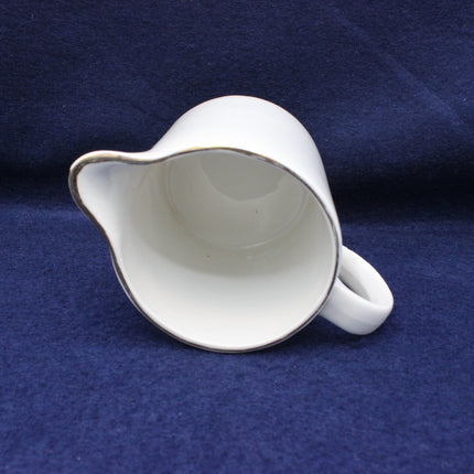 White ceramic pitcher on a blue fabric background