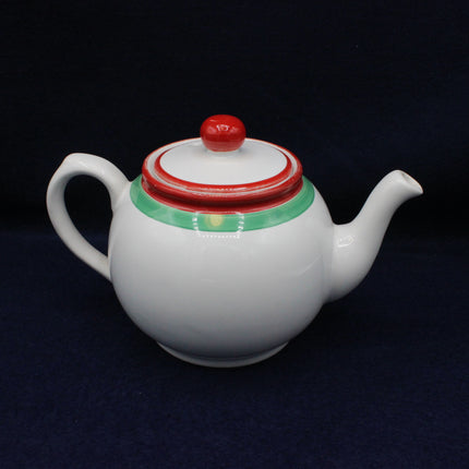 White teapot with a red and green lid on a dark background