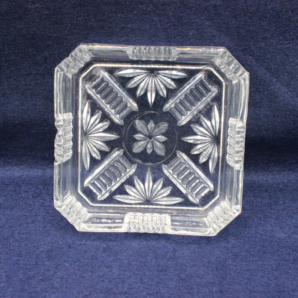 Clear glass ashtray with floral design on a blue background