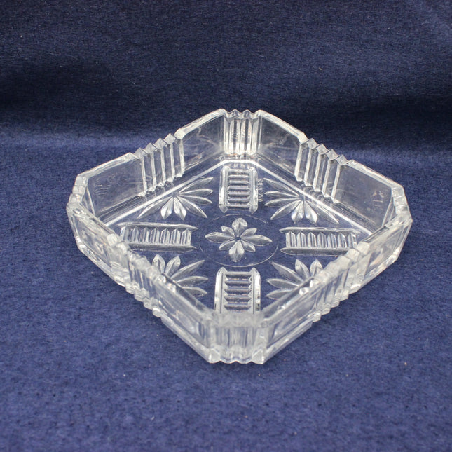 Clear glass hexagonal ashtray with floral patterns on a blue background