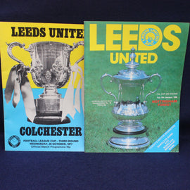 Two Leeds United football club match programs with trophies on a dark background