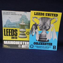 Two Leeds United football club matchday programmes from different matches on a dark background.