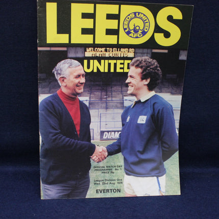 Vintage match day program for Leeds United featuring two men shaking hands on a dark background