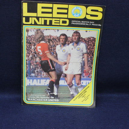 Leeds United football match day programme cover with players and text on a dark background