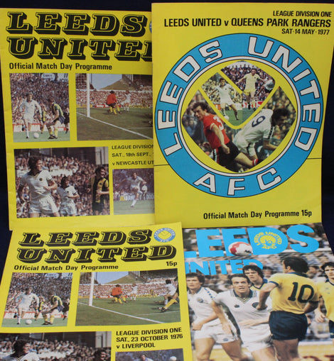 Three Leeds United football match day programmes from different years on a dark background.