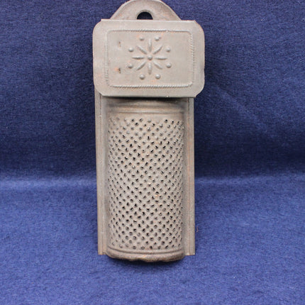 Decorative metal object with textured top and perforated bottom on a blue background