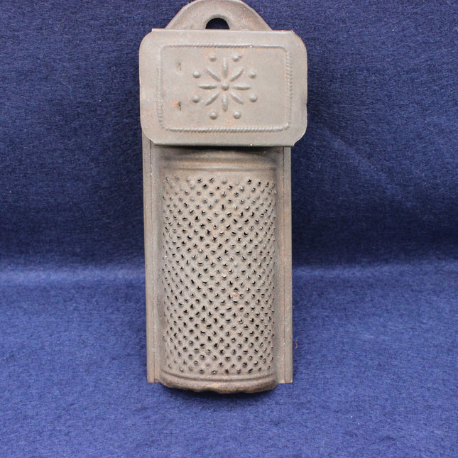 Decorative metal object with textured top and perforated bottom on a blue background