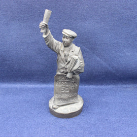 Statue of a paperboy holding a sign and newspaper against a blue background