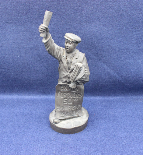 Statue of a paperboy holding a sign and newspaper against a blue background