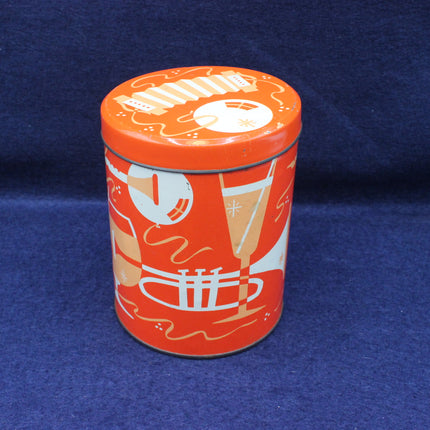 Cylindrical tin can with orange lid and decorative design on a blue background
