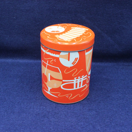 Orange cylindrical tin with decorative design on a blue background