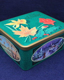Decorative tin box with floral and landscape designs on a blue background