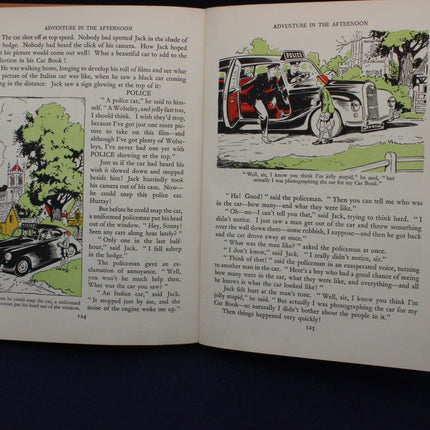 Open book with illustrated pages featuring a car and people, likely from a children's storybook.