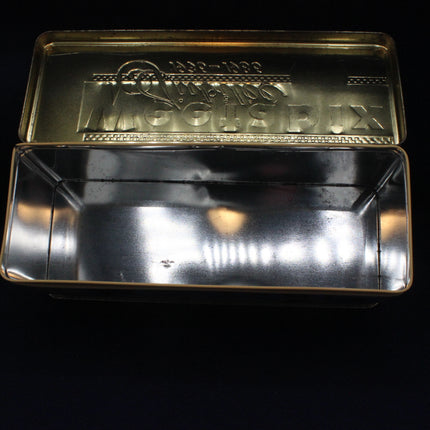 Metallic tray with a gold lid featuring branding on a black background