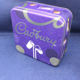 Purple Cadbury tin with white text and logo on a blue background
