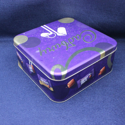 Purple tin box with 'Dairy Milk' branding on a blue background
