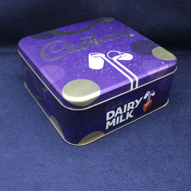 Purple Cadbury Dairy Milk chocolate tin on a blue background