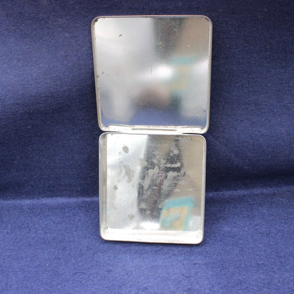 Silver compact mirror with a blue background