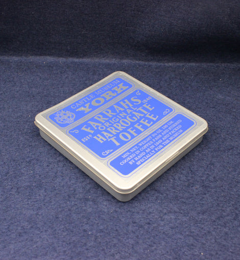 Box of Harrogate Toffee with blue label on a dark blue fabric background