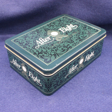 Green After Eight tin box with decorative patterns on a purple background