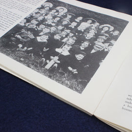 Open book with a black and white photograph of a group of people on a blue fabric background