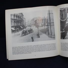 Open book showing black and white photograph of a street scene with people and vehicles.