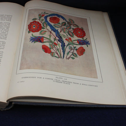 Open book with an embroidered design of flowers and a snake on a beige background.