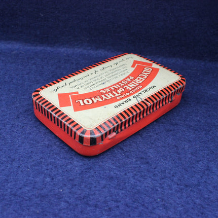 Vintage red and white tin box with text on a blue background