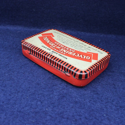Small rectangular tin with a red and black striped design on a blue background