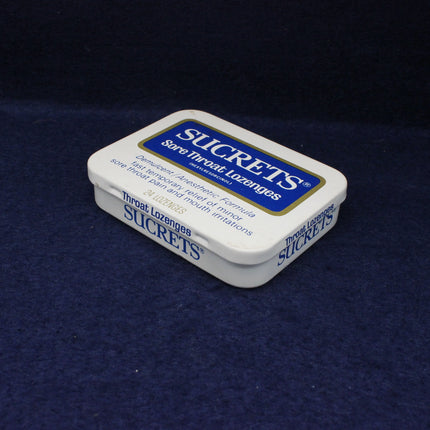 Sucrets sore throat lozenges container on a dark blue background