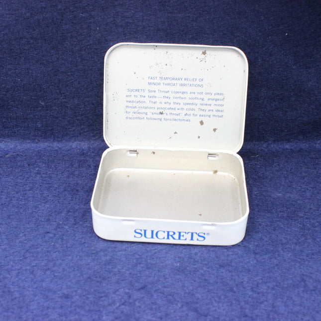 Open white Sucrets container on a blue background