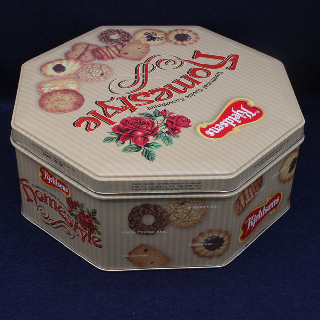 Decorative cookie tin with brand logo on a dark background