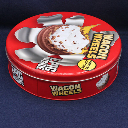 Wagon Wheels cookie tin with a red lid featuring an image of a cookie and text on a dark blue background.