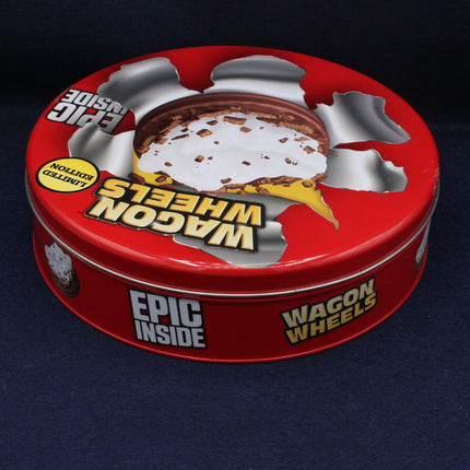Red tin container of Wagon Wheels with a bite taken out of it on a dark background
