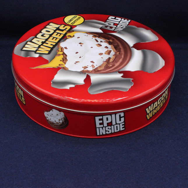 Red tin container with 'Wagon Wheels' branding on a dark blue background