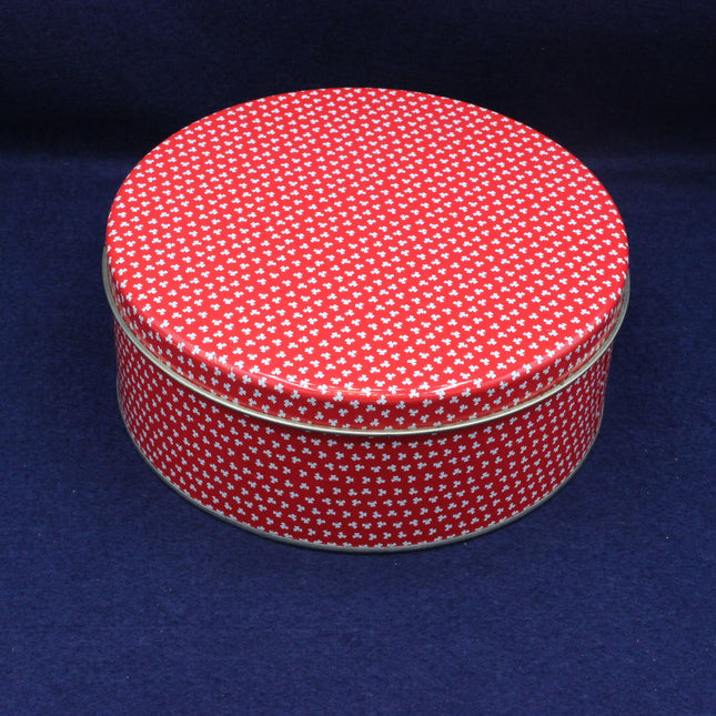Round tin with red and white pattern on a blue background