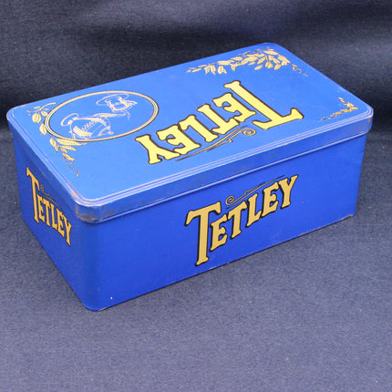 Blue metal tin with 'Tetley' branding on a dark background